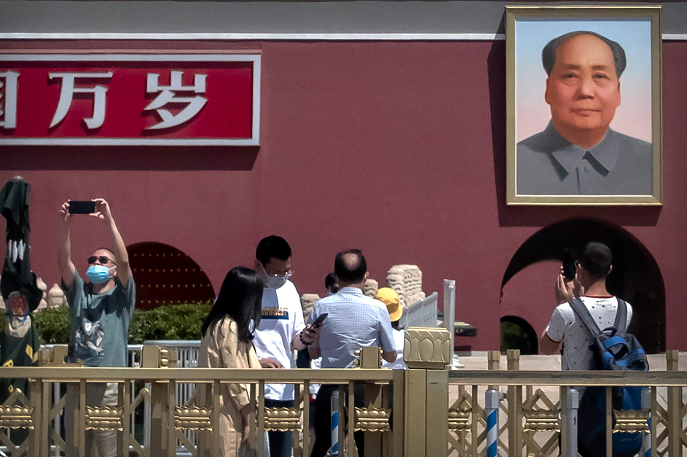 Visitors wearing face masks to protect against the spread of the new coronavirus take photos near the portrait of Chinese leader Mao Zedong on Tiananmen Gate in Beijing, Wednesday, May 20, 2020. China's rubber-stamp legislature is set to begin its annual session on Friday after being delayed several months amid the coronavirus outbreak. (AP Photo/Mark Schiefelbein)