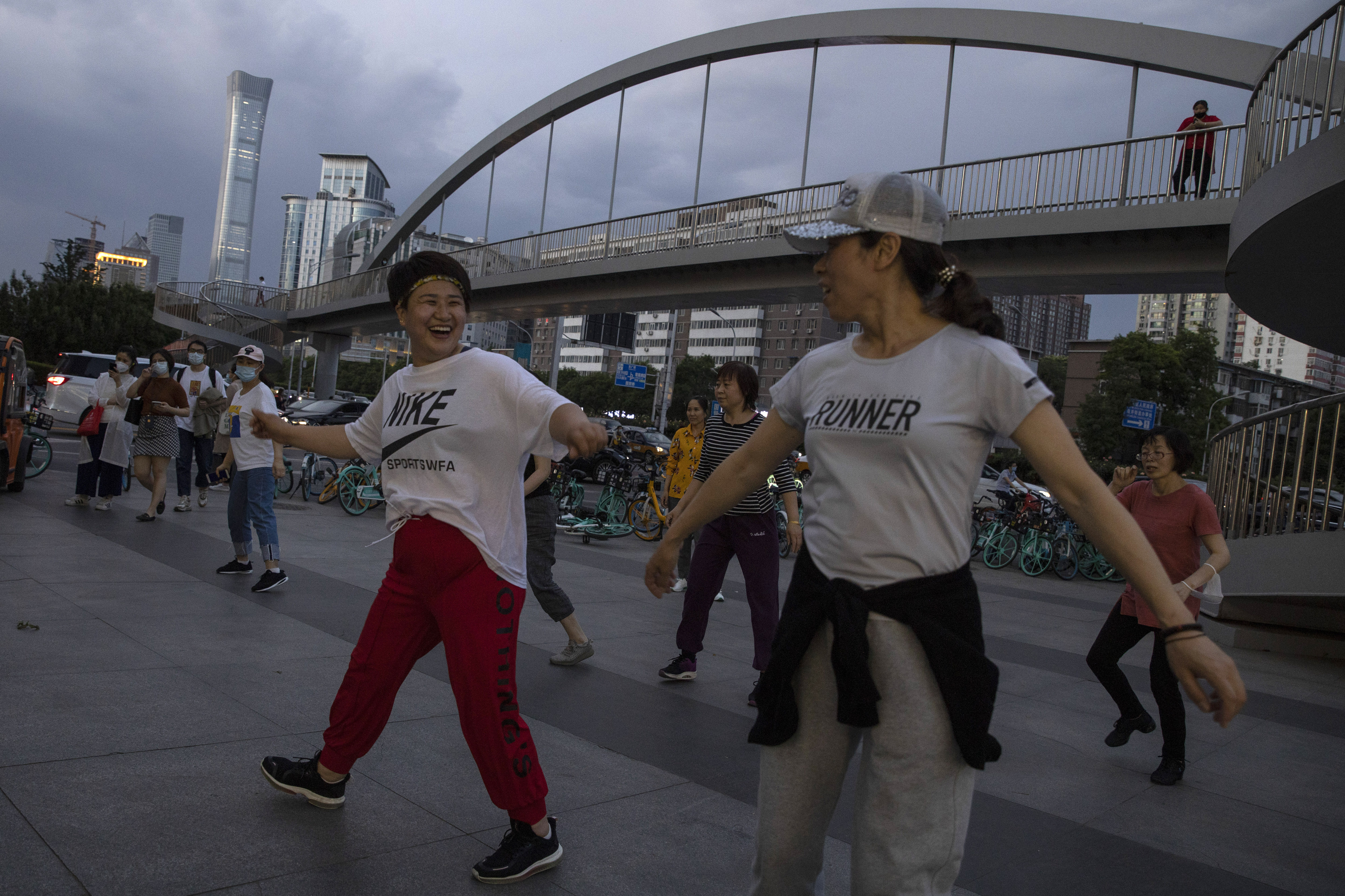 In this Tuesday, May 19, 2020, Chinese residents take part in plaza dance routines on the streets of Beijing, China. This year's version of China's biggest political meeting of the year will be unlike any other. Delayed from March because of the then-spiraling coronavirus outbreak, the decision to go ahead with the gathering signals a partial return to normalcy in the country where the pandemic first broke out. 