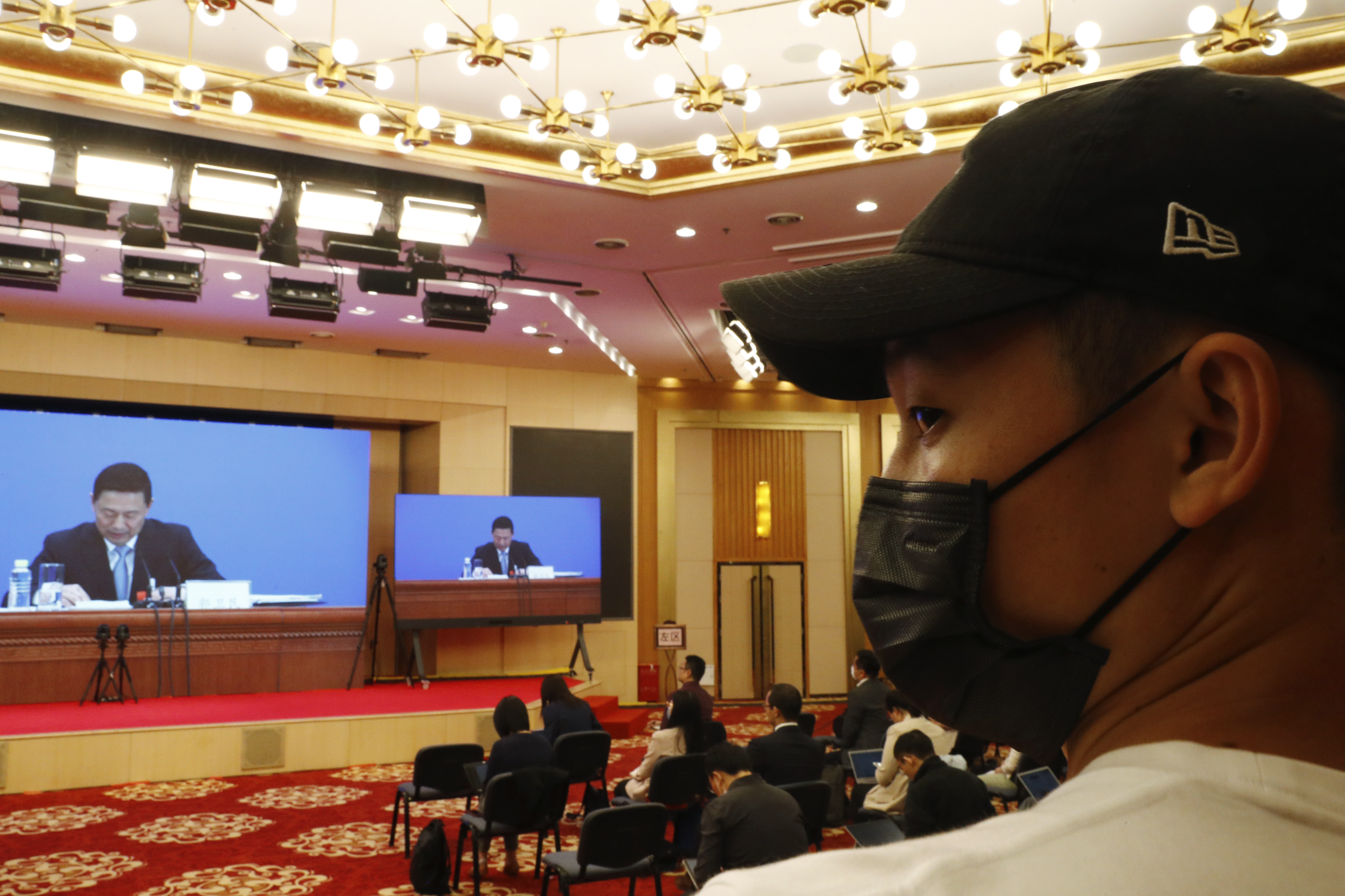A journalist wearing a face mask following the coronavirus outbreak attends a news conference by Guo Weimin, spokesman for the National Committee of the Chinese People's Political Consultative Conference (CPPCC), broadcasted at a media center in Beijing, China Wednesday, May 20, 2020. This year’s version of the National People’s Congress — China’s biggest political meeting of the year — will be unlike any other. Delayed from March because of the then-spiraling coronavirus outbreak, the decision to go ahead with the annual gathering starting Friday signals a partial return to normalcy in the country where the pandemic first broke out. (Thomas Peter/Pool Photo via AP)