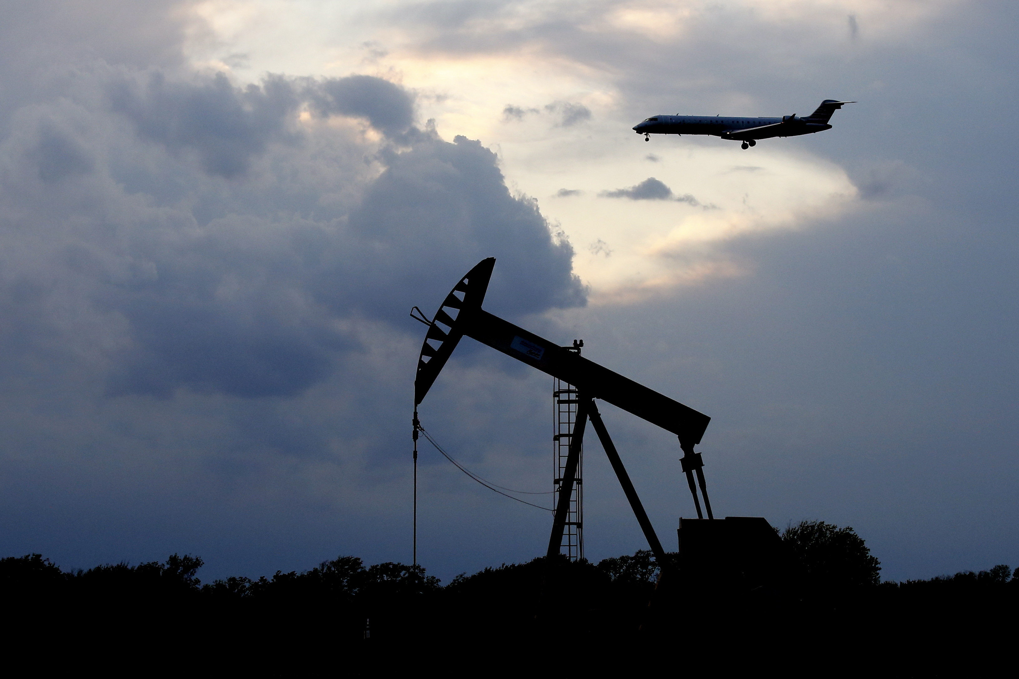A plane comes in for a landing behind a pumpjack Tuesday, April 21, 2020, in Oklahoma City. Oil prices continue to drop, because very few people are flying or driving, and factories have shut amid widespread stay-at-home orders due to the coronavirus concerns. (AP Photo/Sue Ogrocki)