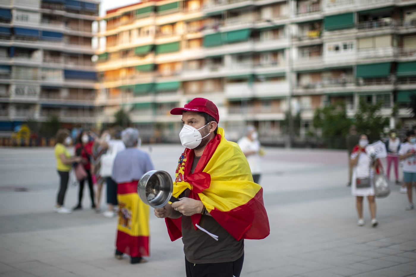 A man with a Spanish flag on his shoulders and banging a saucepan takes part in a protest against the Spanish government amid the lockdown to prevent the spread of coronavirus in Alcorcon, Spain, Friday, May 22, 2020. The Spanish government is allowing Madrid and Barcelona to ease their lockdown measures, which were introduced to fight the coronavirus pandemic. (AP Photo/Manu Fernandez)