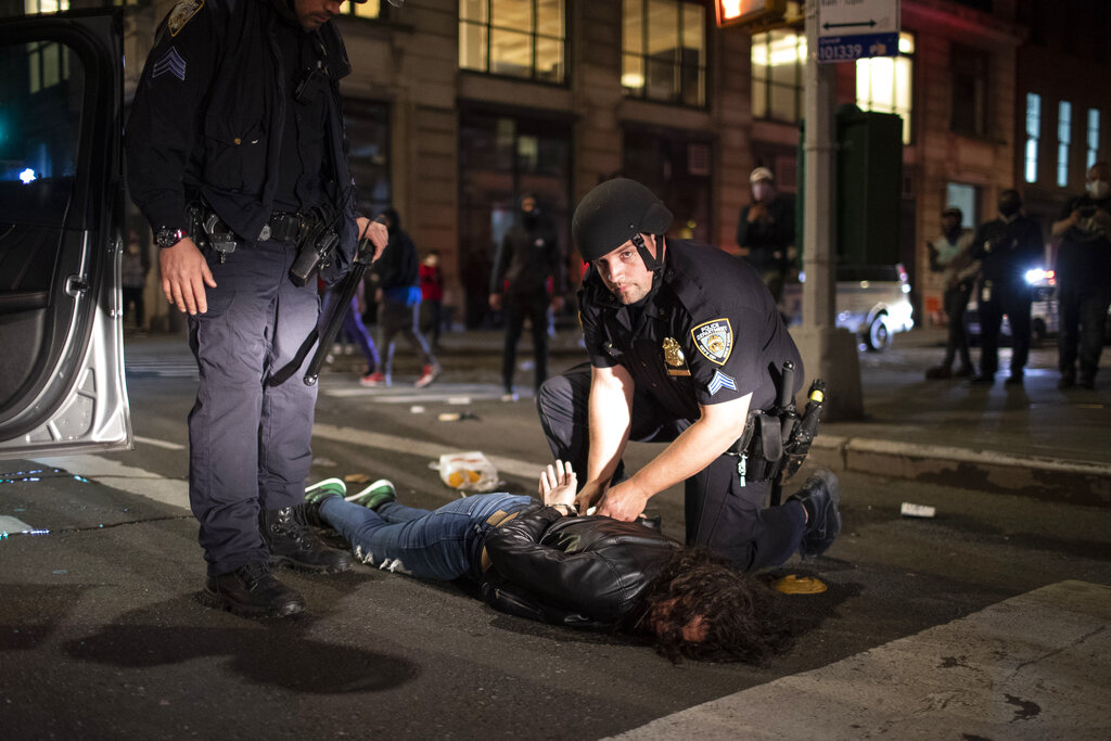 A woman is arrested after being pulled out of a passenger seat for reckless driving as protesters take to the streets in SoHo on Sunday, May 31, 2020, in New York. Protests were held throughout the city over the death of George Floyd, a black man in police custody in Minneapolis who died after being restrained by police officers on Memorial Day. (AP Photo/Wong Maye-E)