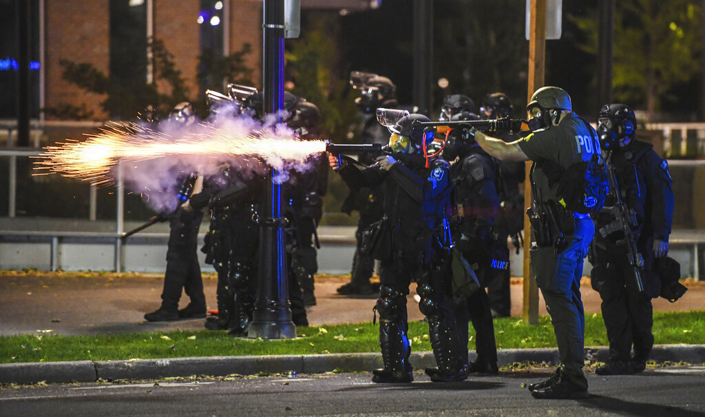 Police officers fire upon advancing protesters after warning them to move back, Sunday, May 31, 2020, in Spokane, Wash. during a protest over the death of George Floyd on May 25. (Dan Pelle/The Spokesman-Review via AP)