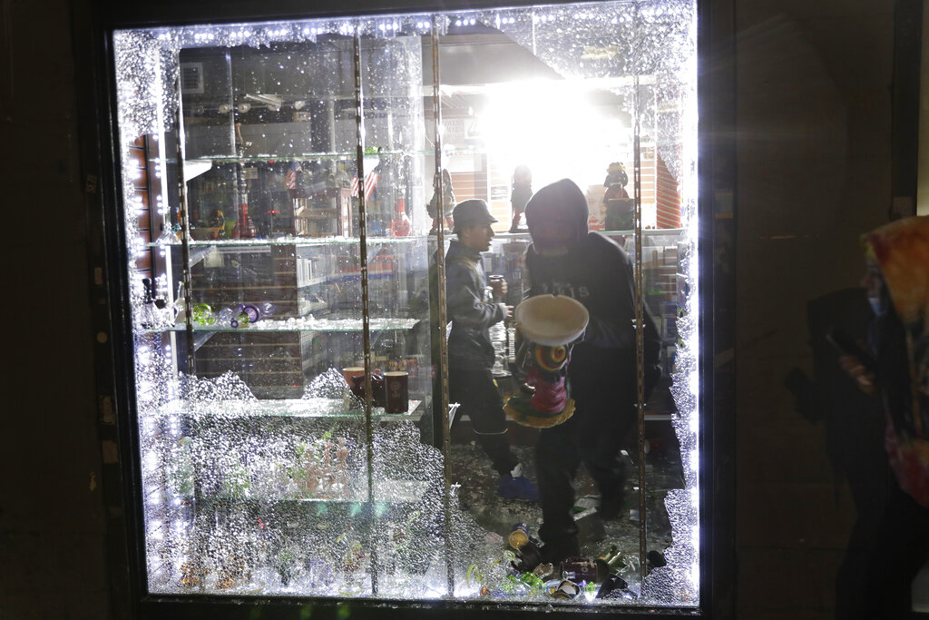 People carry things out of a smoke shop through a broken window in New York, Monday, June 1, 2020. Demonstrators took to the streets of New York City to protest the death of George Floyd, a black man who died in police custody in Minneapolis on May 25. (AP Photo/Seth Wenig)