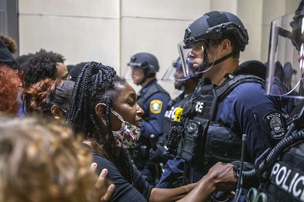 A protester holds a police officer's hand while praying together during a rally to protest the deaths of George Floyd and Breonna Taylor in Lexington, Ky., on Sunday, May 31, 2020. (Ryan C. Hermens/Lexington Herald-Leader via AP)