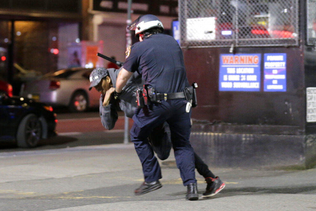 A police officer tackles a suspect trying to escape in New York, Monday, June 1, 2020. A fourth day of protests against police brutality kept New York City on edge Sunday, as thousands of people marched and many protesters and officers tried to keep the peace after days of unrest that left police cars burned and hundreds of people under arrest. (AP Photo/Seth Wenig)