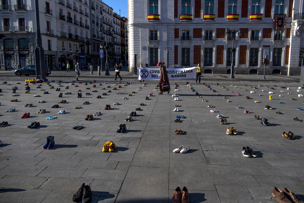 A man walks among shoes during the performance by the group Members of Extinction Rebellion 