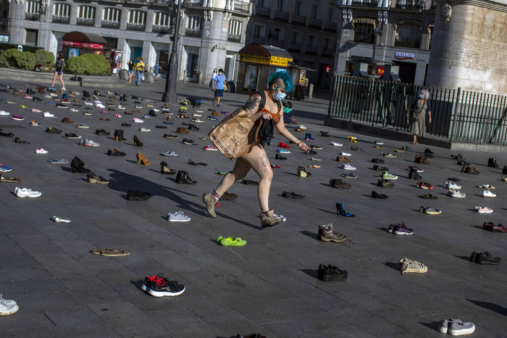 A member of the Extinction Rebellion group walks among shoes during the performance 