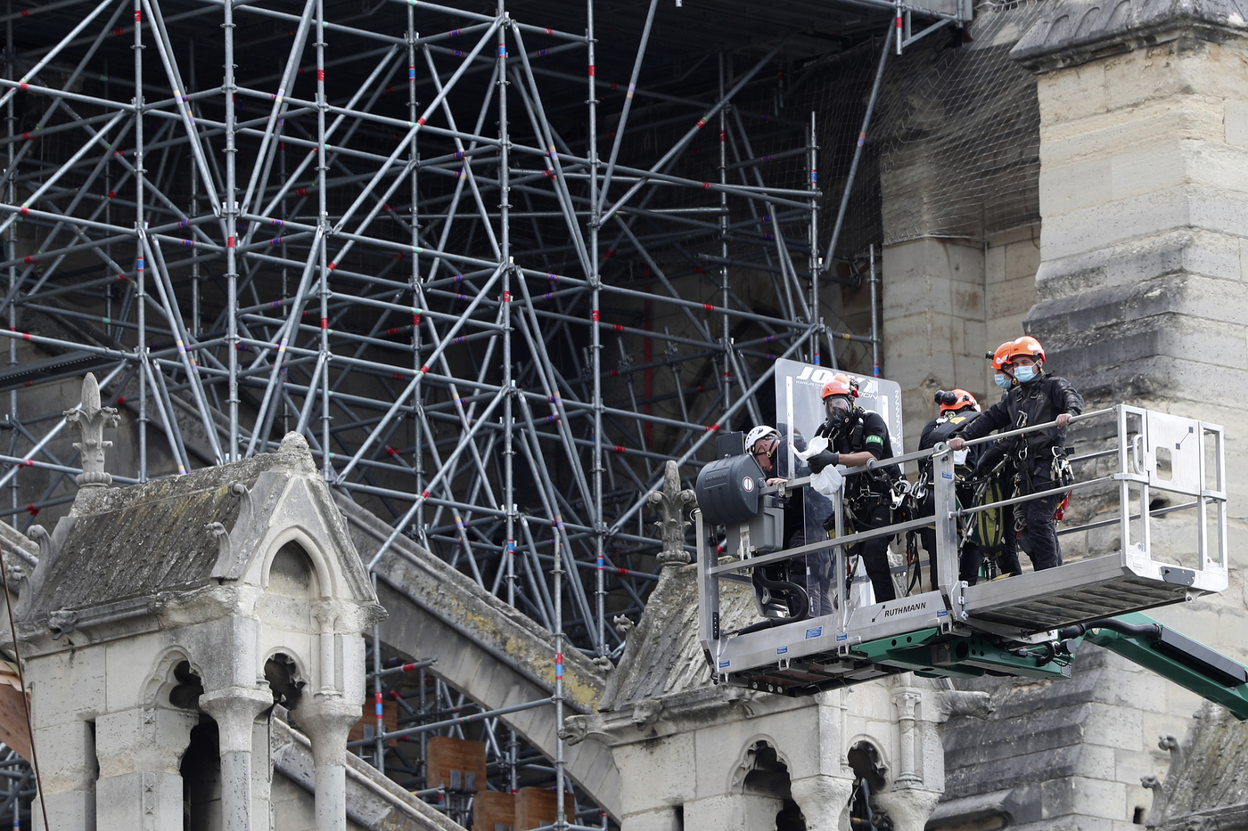 Workers are lifted Notre Dame cathedral, Monday, June 8, 2020 in Paris. Workers suspended from ropes will be lowered into the charred remains of scaffolding that melted atop Notre Dame when the cathedral went up in flames and begin the delicate job of dismantling the 200 tons of metal. (AP Photo/Thibault Camus)