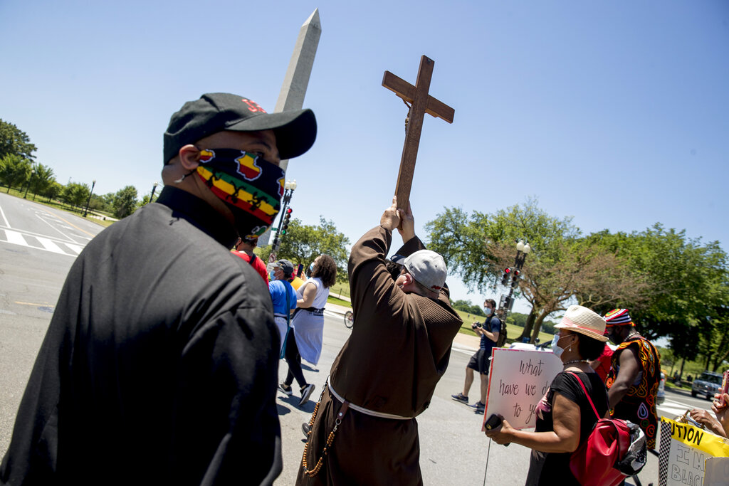 The Washington Monument is visible as members of the Archdiocese of Washington march from the White House to the Smithsonian National Museum of African American History and Culture, Monday, June 8, 2020, in Washington, after days of protests over the death of George Floyd, a black man who was in police custody in Minneapolis. Floyd died after being restrained by Minneapolis police officers. (AP Photo/Andrew Harnik)