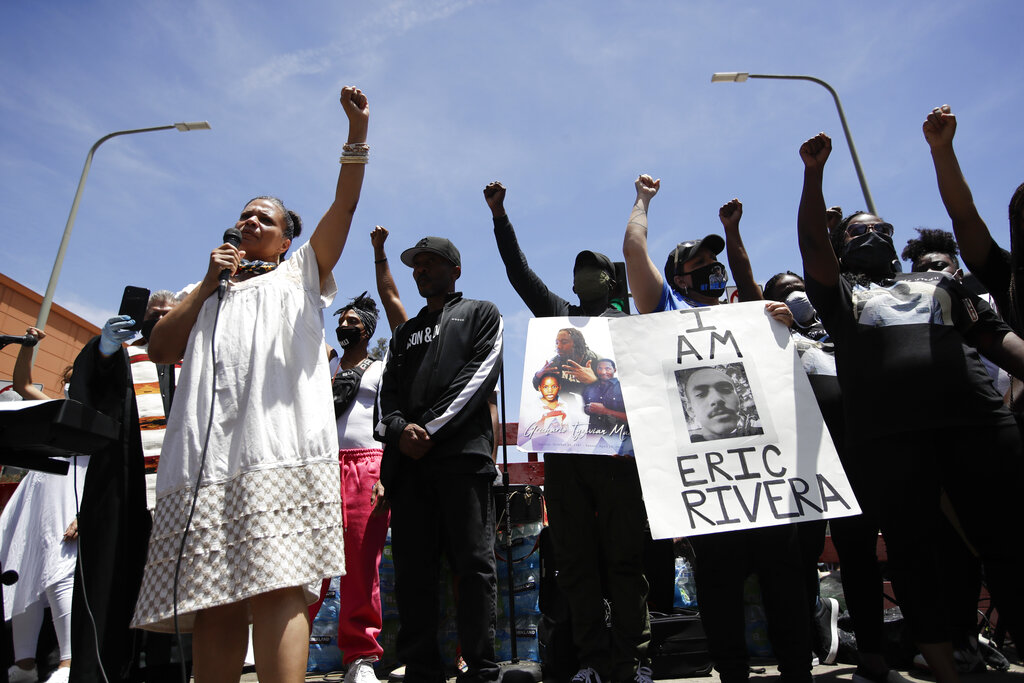 Melina Abdullah, left, of Black Lives Matter Los Angeles, leads a crowd in a raising of fists Monday, June 8, 2020, in Los Angeles during a protest over the death of George Floyd who died May 25 after he was restrained by Minneapolis police.. (AP Photo/Marcio Jose Sanchez)