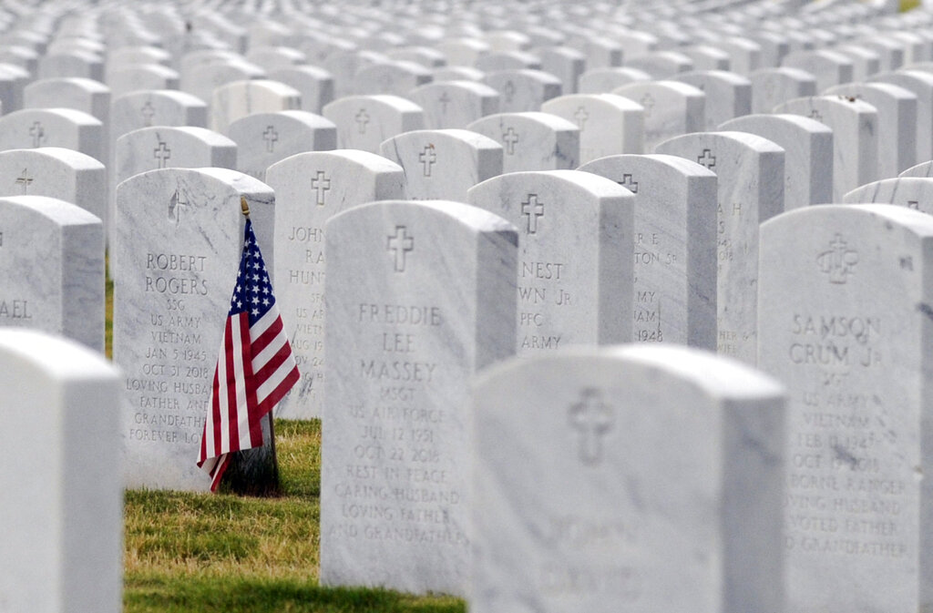 this May 22, 2020 photo, a U.S. flag decorates a veteran's grave at Alabama National Cemetery in Montevallo, Ala. Because of the coronavirus pandemic, the government has banned public ceremonies and the mass placement of flags on graves at the country's 142 national cemeteries. With almost 4.9 million people interred in the cemeteries, thousands would attend memorial events and help mark graves with flags during a typical Memorial Day weekend. (AP Photo/Jay Reeves)