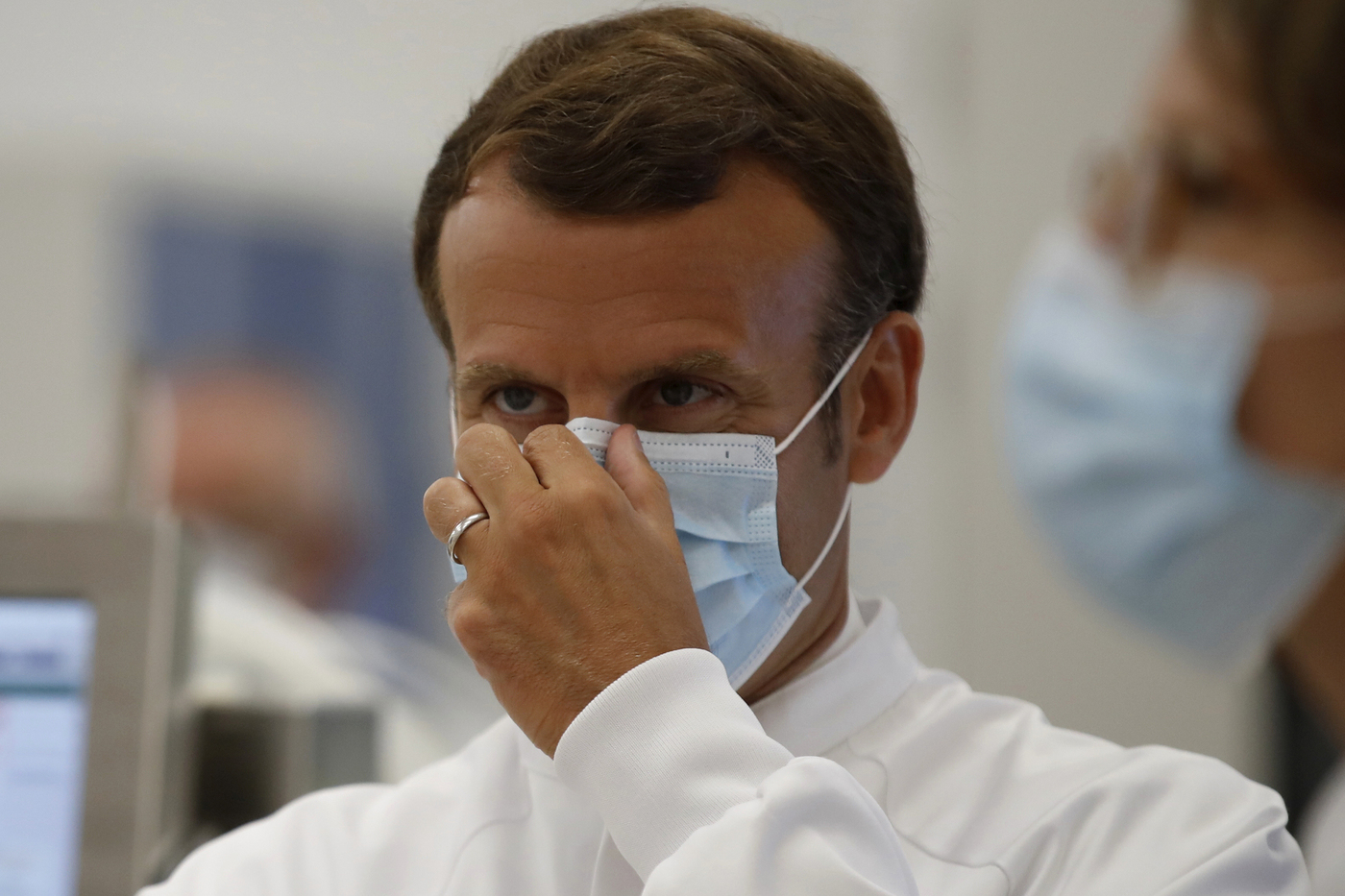 French President Emmanuel Macron adjusts his protective mask as he visits an industrial development laboratory at the French drugmaker's vaccine unit Sanofi Pasteur plant in Marcy-l'Etoile, near Lyon, central France, Tuesday, June 16, 2020. The visit comes after rival pharmaceutical company AstraZeneca this weekend announced a deal to supply 400 million vaccine doses to EU countries, including France. (Gonzalo Fuentes/Pool via AP)