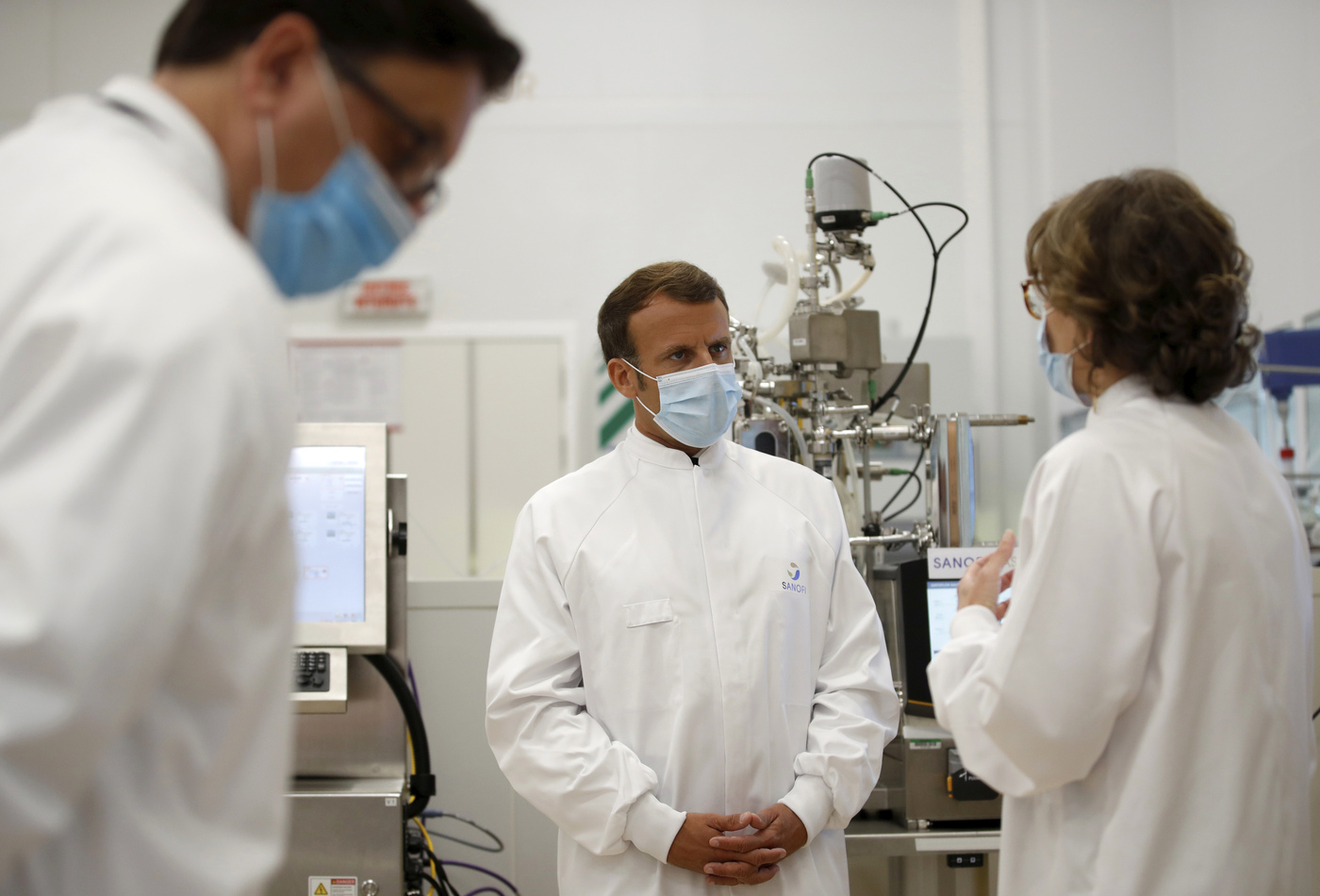 French President Emmanuel Macron, wearing a protective face mask, listens to researchers as he visits an industrial development laboratory at the French drugmaker's vaccine unit Sanofi Pasteur plant in Marcy-l'Etoile, near Lyon, central France, Tuesday, June 16, 2020. The visit comes after rival pharmaceutical company AstraZeneca this weekend announced a deal to supply 400 million vaccine doses to EU countries, including France. (Gonzalo Fuentes/Pool via AP)