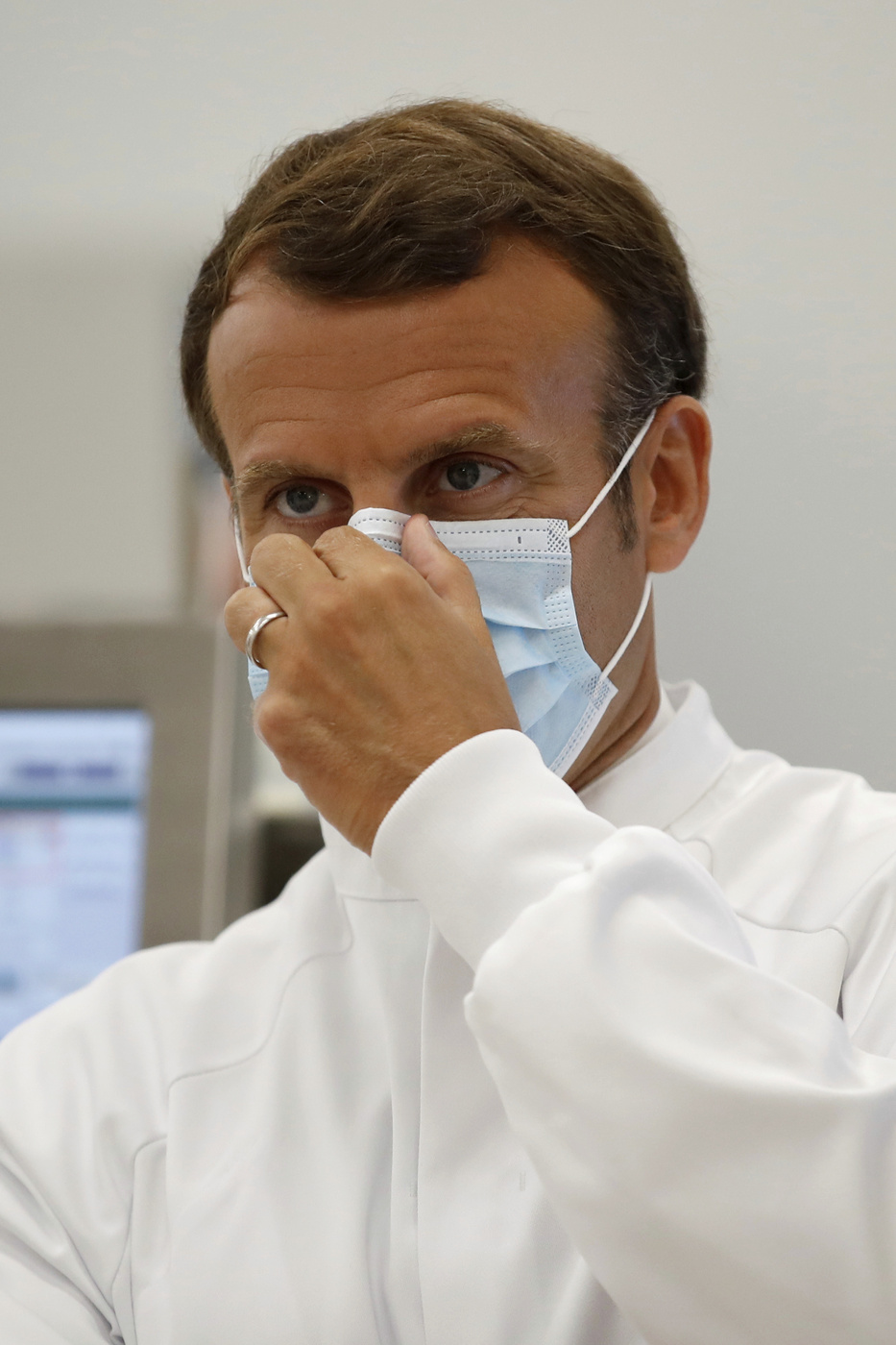 French President Emmanuel Macron adjusts his mask as he visits an industrial development laboratory at the French drugmaker's vaccine unit Sanofi Pasteur plant in Marcy-l'Etoile, near Lyon, central France, Tuesday, June 16, 2020. The visit comes after rival pharmaceutical company AstraZeneca this weekend announced a deal to supply 400 million vaccine doses to EU countries, including France. (Gonzalo Fuentes/Pool via AP)