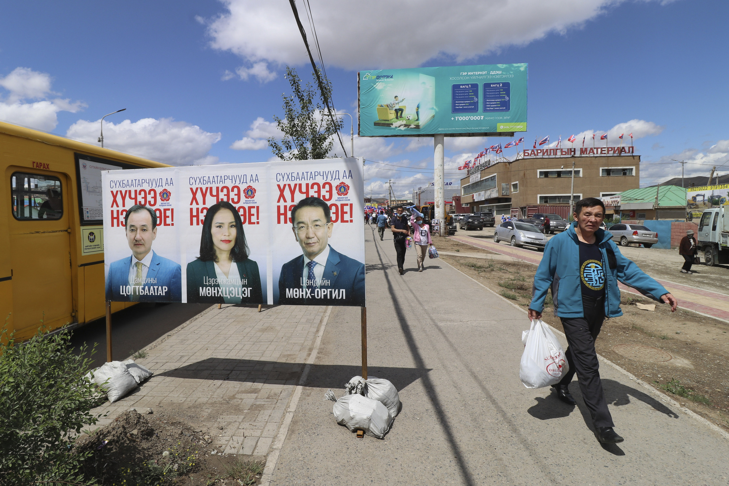 A man walks past an election poster of candidates of the ruling Mongolian People's Party (MPP) featuring current Foreign Minister Damdiny Tsogtbaatar, left, in the Chingeltei district, northern outskirts of Ulaanbaatar, Mongolia, Monday, June 22, 2020. Mongolia holds parliamentary elections on Wednesday, continuing a nearly 30-year democratic system in a vast but lightly populated country sandwiched between authoritarian regimes in Russia and China and beset by economic problems. (AP Photo/Ganbat Namjilsangarav)