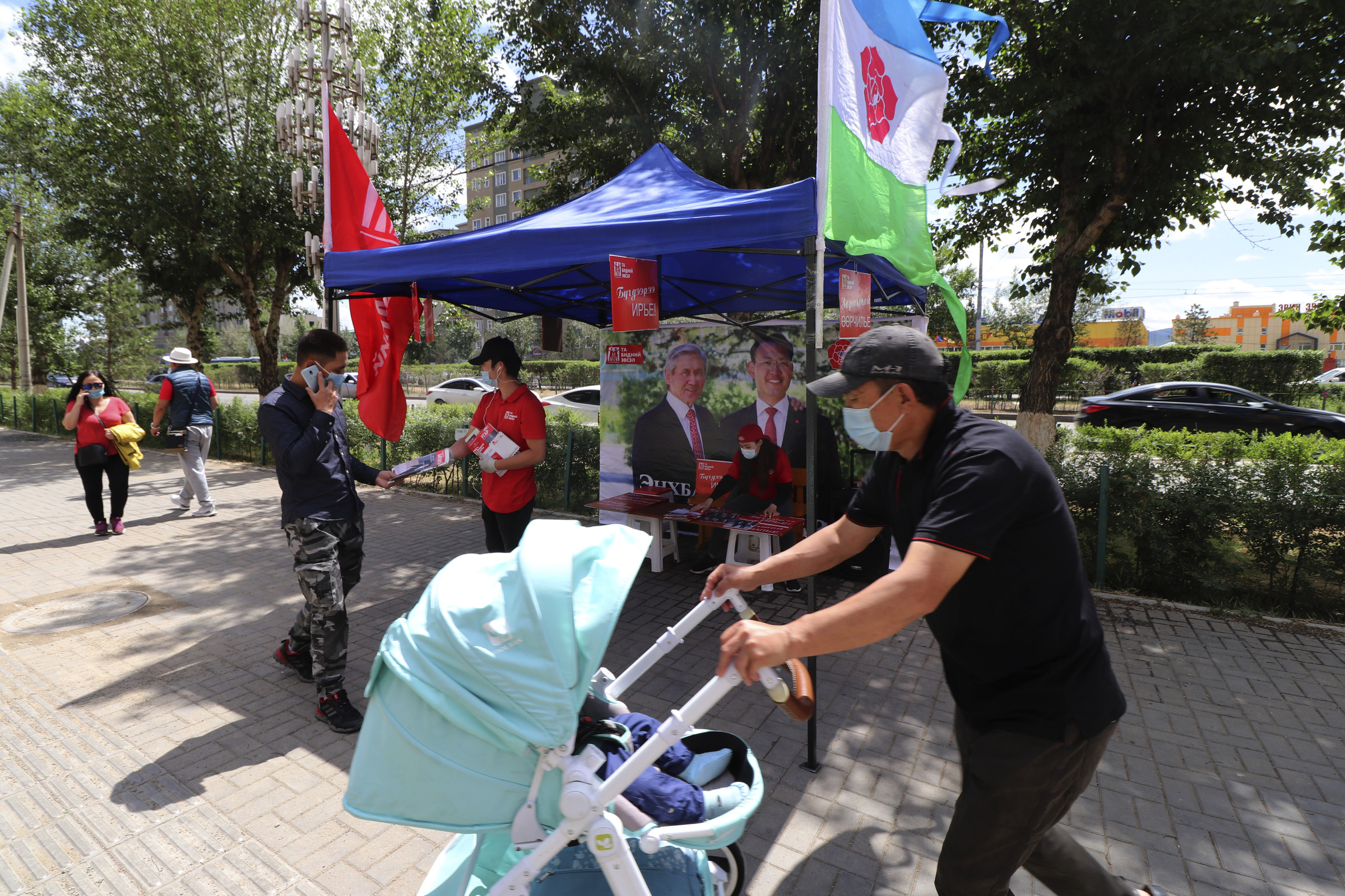 Election workers of Mongolian People's Revolutionary Party (MPRP) distribute election brochures on the downtown street of Ulaanbaatar, Mongolia, Monday, June 22, 2020. Mongolia holds parliamentary elections on Wednesday, continuing a nearly 30-year democratic system in a vast but lightly populated country sandwiched between authoritarian regimes in Russia and China and beset by economic problems. (AP Photo/Ganbat Namjilsangarav)
