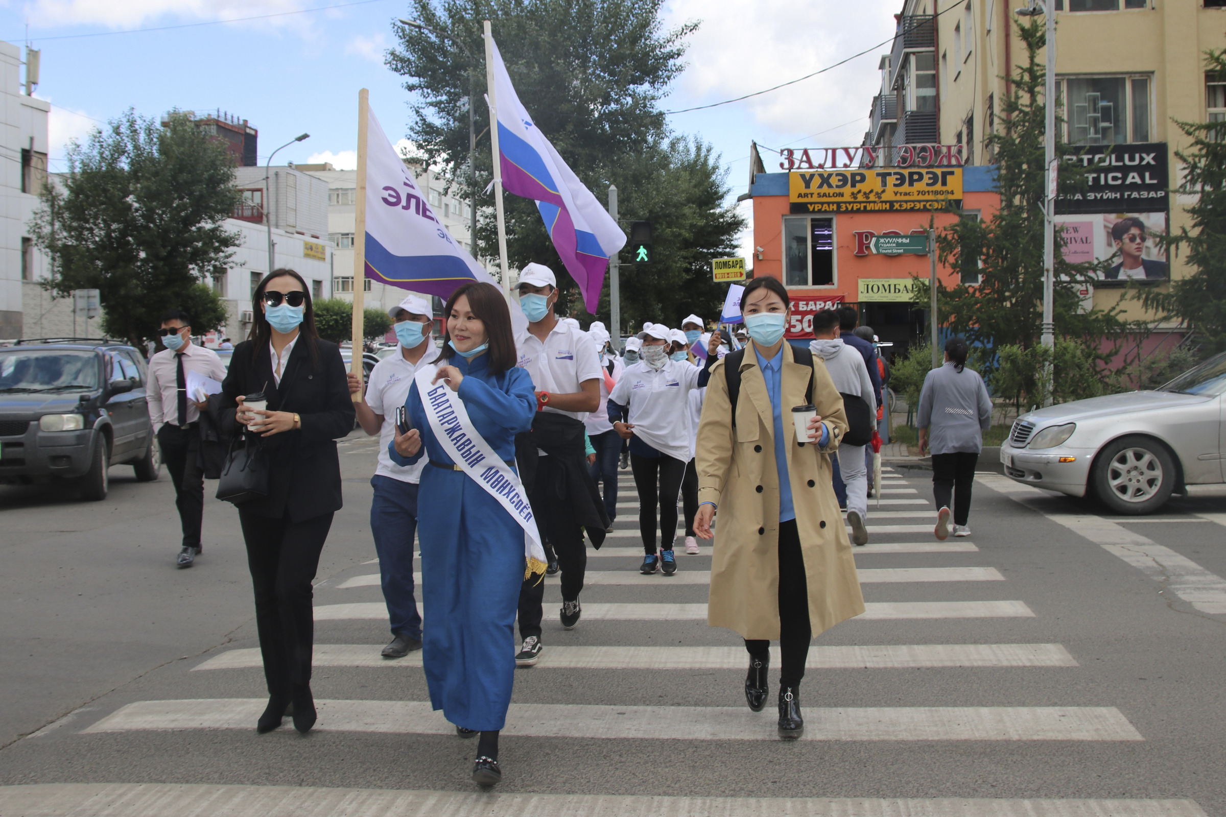 Munkhsoyol Baatarjav, female candidate of "Right person-Electorate" coalition led by National Labor Party, wearing long blue robe and white ribbon, walks with her supporters along the downtown street of Ulaanbaatar, Mongolia, Monday, June 22, 2020. Mongolia holds parliamentary elections on Wednesday, continuing a nearly 30-year democratic system in a vast but lightly populated country sandwiched between authoritarian regimes in Russia and China and beset by economic problems. (AP Photo/Ganbat Namjilsangarav)