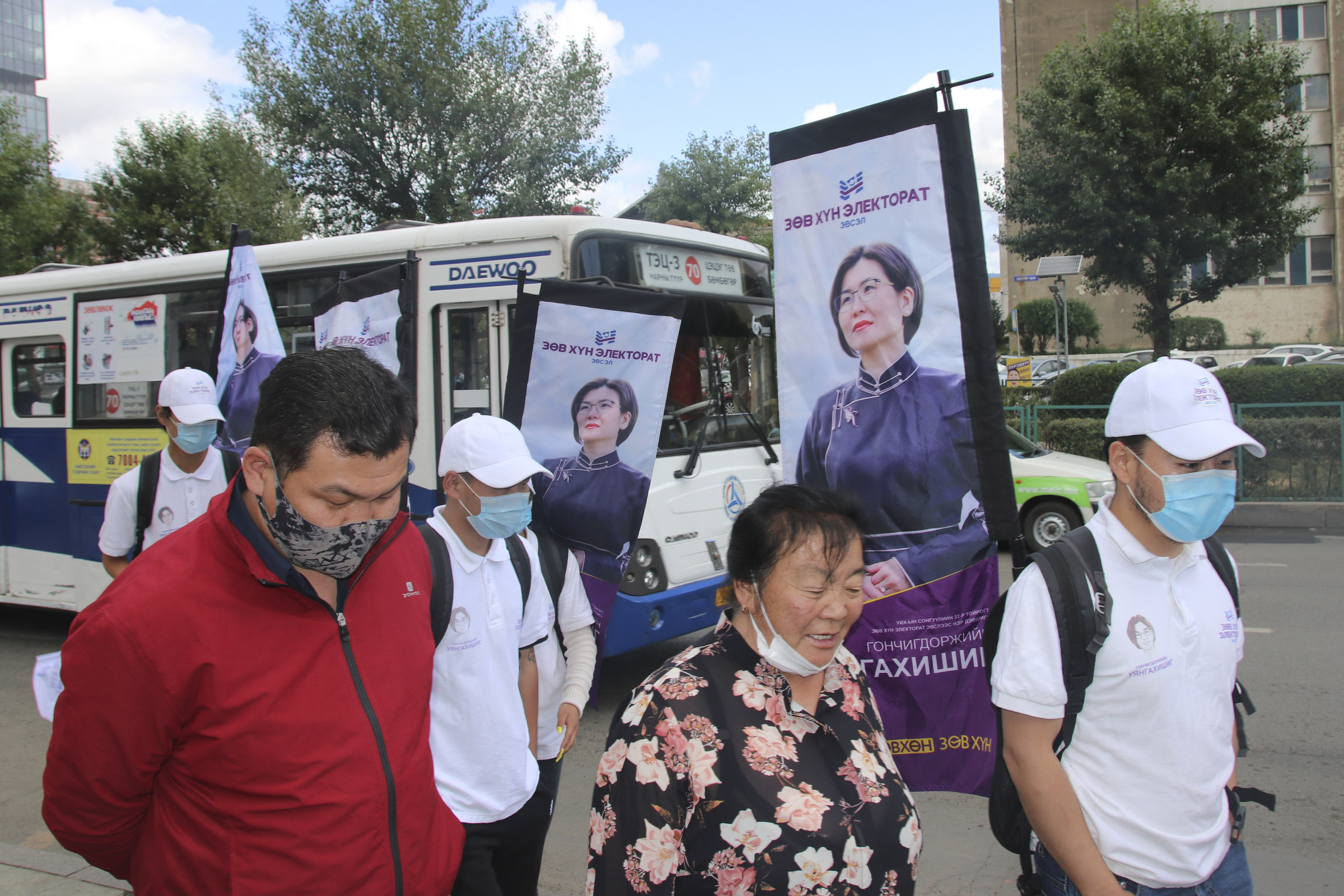 Campaign workers and supporters of "Right person-Electorate" coalition led by National Labor Party parade with posters of their candidates and coalition symbols on the downtown street of Ulaanbaatar, Mongolia, Monday, June 22, 2020. Mongolia holds parliamentary elections on Wednesday, continuing a nearly 30-year democratic system in a vast but lightly populated country sandwiched between authoritarian regimes in Russia and China and beset by economic problems. (AP Photo/Ganbat Namjilsangarav)