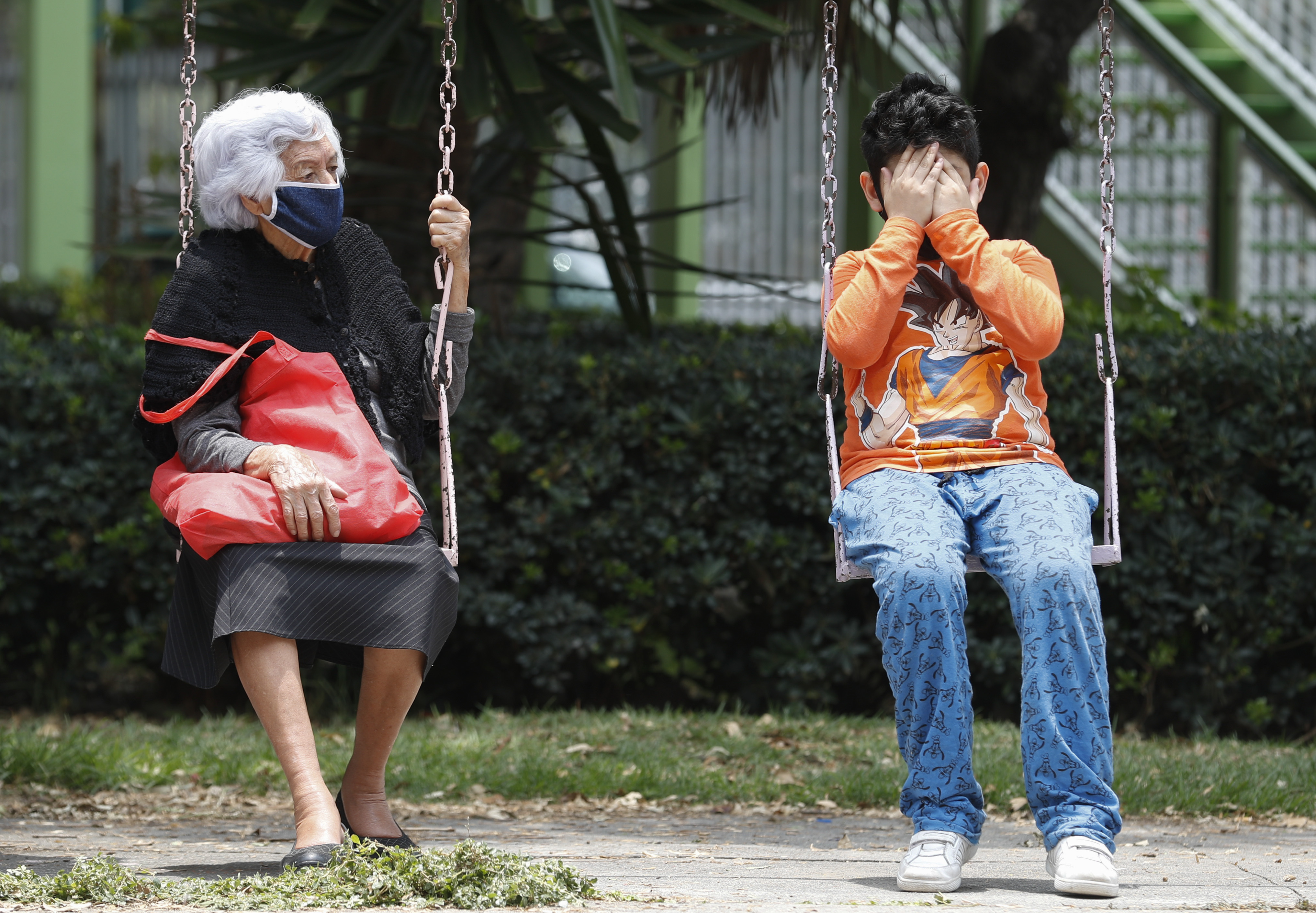 A woman and boy sit on a set of swings as they wait for the all-clear to return to their apartment, after an earthquake in Mexico City, Tuesday, June 23, 2020. The earthquake struck near the Huatulco resort in southern Mexico on Tuesday morning, swayed buildings in Mexico City and sent thousands fleeing into the streets. (AP Photo/Eduardo Verdugo)