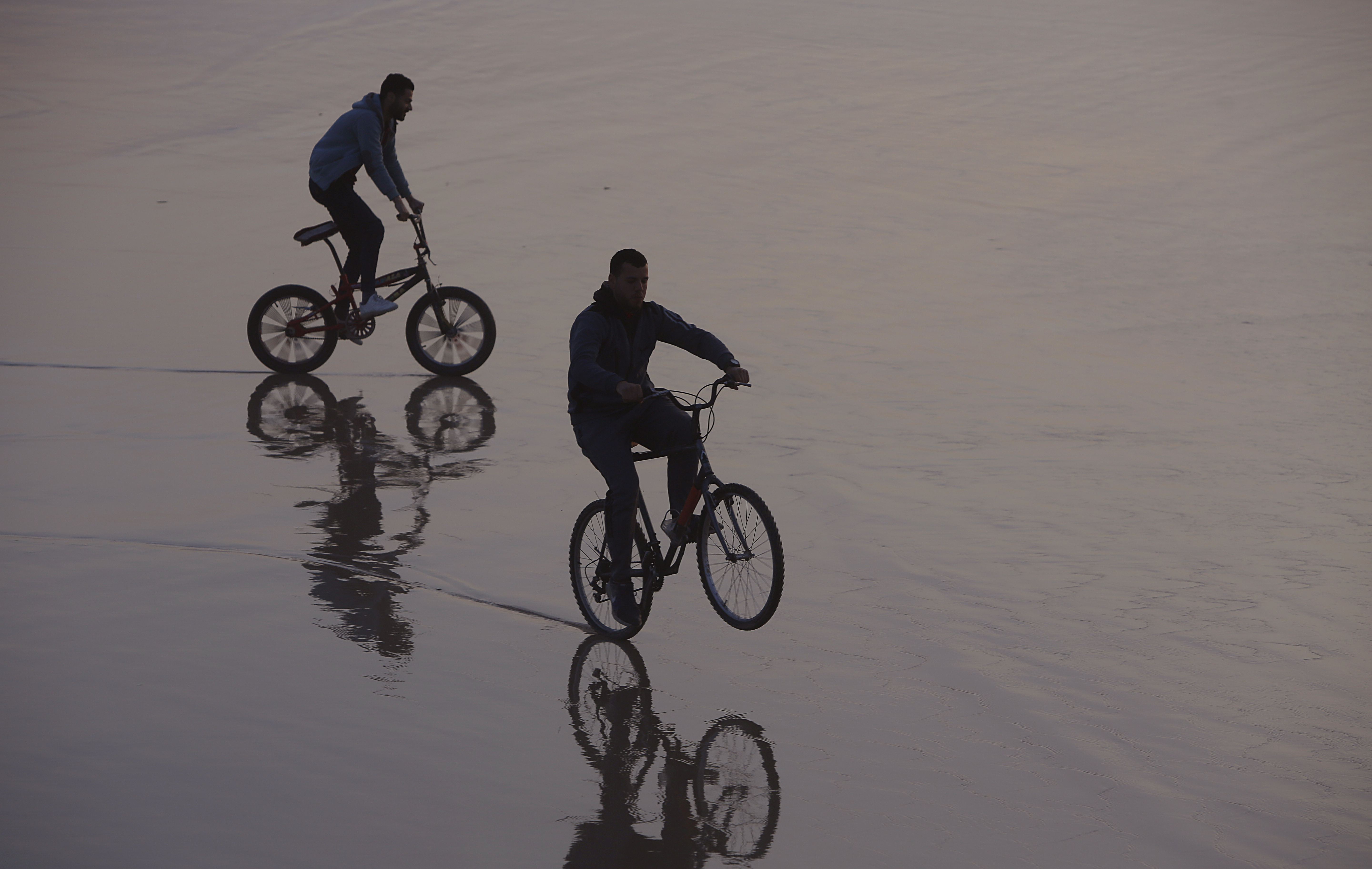 Palestinians ride their bicycles during the sunset at the beach, in Gaza City, Saturday, Feb.22, 2020. The beach is one of the few open public spaces in this densely populated city. (AP Photo/Hatem Moussa)