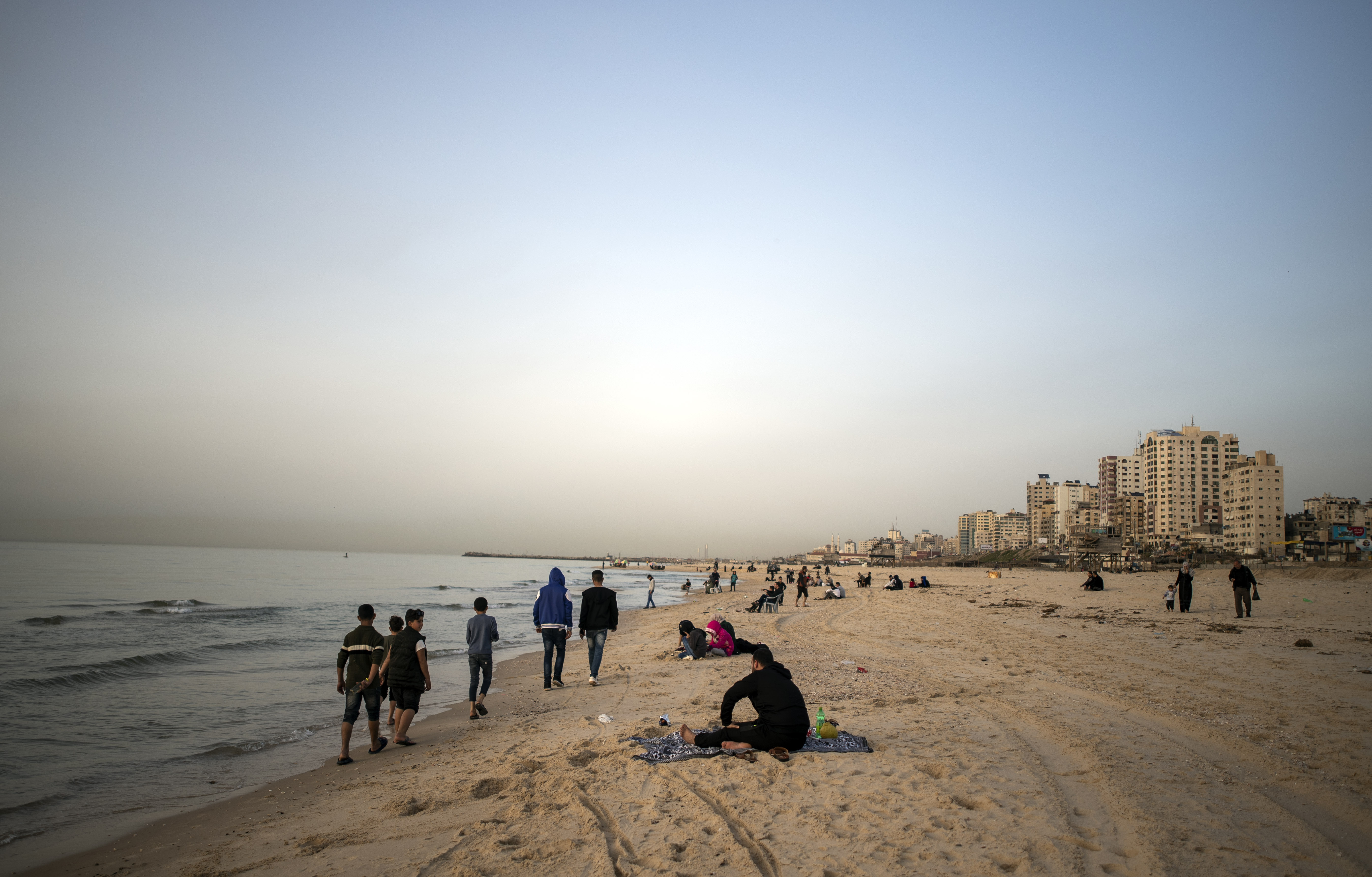 Palestinians spend a warm day on the beach as the sun sets over the Mediterranean Sea in Gaza City, Monday, March 23, 2020. (AP Photo/Khalil Hamra)