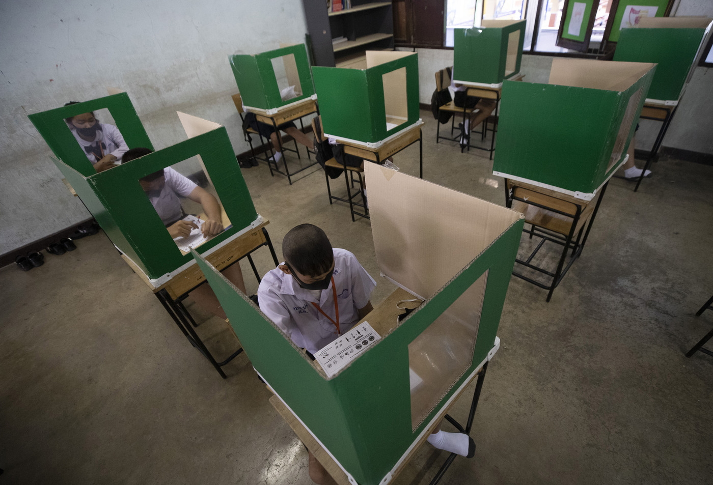 Students in a protective gear are seated at partitioned desks at the Samkhok School in Pathum Thani, outside Bangkok, Wednesday, July 1, 2020. Thailand has begun a fifth phase of relaxations of COVID-19 restrictions, allowing the reopening of schools and high-risk entertainment venues such as pubs and massage parlors that had been shut since mid-March. (AP Photo/Sakchai Lalit)