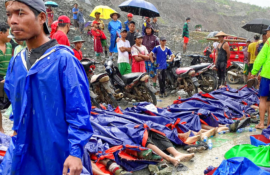 People walk and gather near dead bodies of jade scavengers who were killed in a landslide covered with plastic and lined up near a jade mining area Thursday, July 2, 2020, in Hpakant, Kachine state in northern Myanmar. Myanmar government says a landslide at a jade mine in the country’s north has killed 50 people. The Ministry of Information cited the local fire service at the site of Thursday’s landslide in Hpakant in Kachin state.(AP Photo/Zaw Moe Htet)