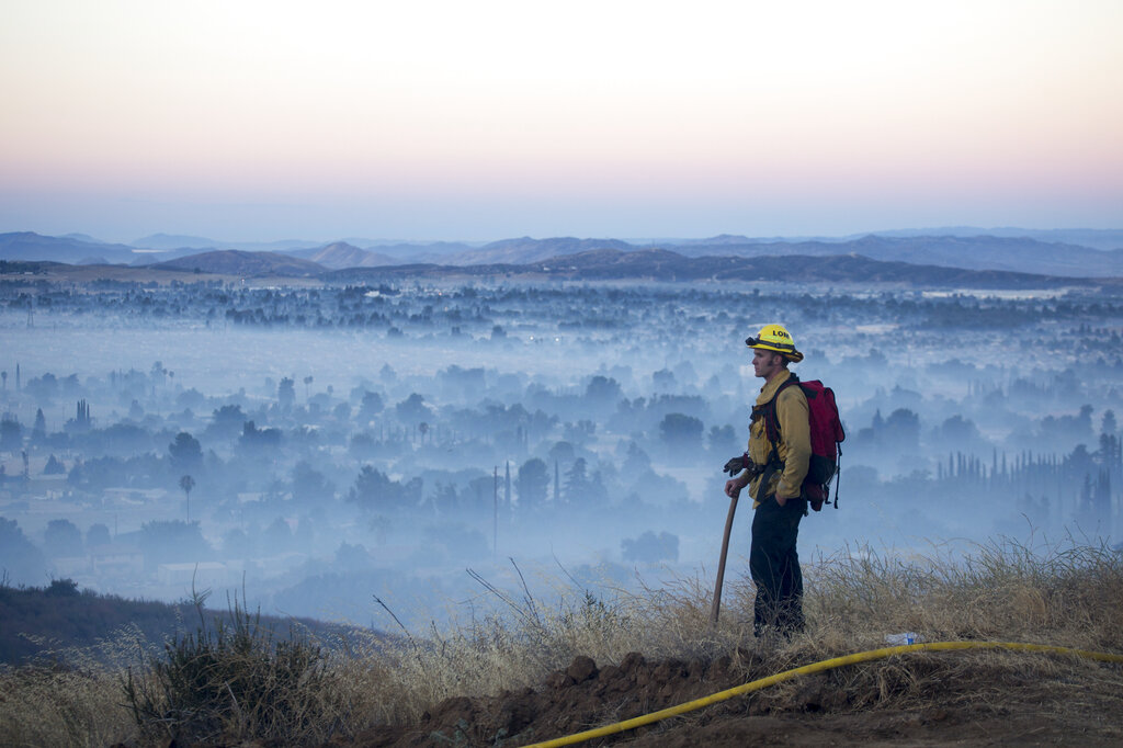 A firefighter watches as smoke from the Apple Fire covers the city in Banning, Calif., Saturday, Aug. 1, 2020. (AP Photo/Ringo H.W. Chiu)