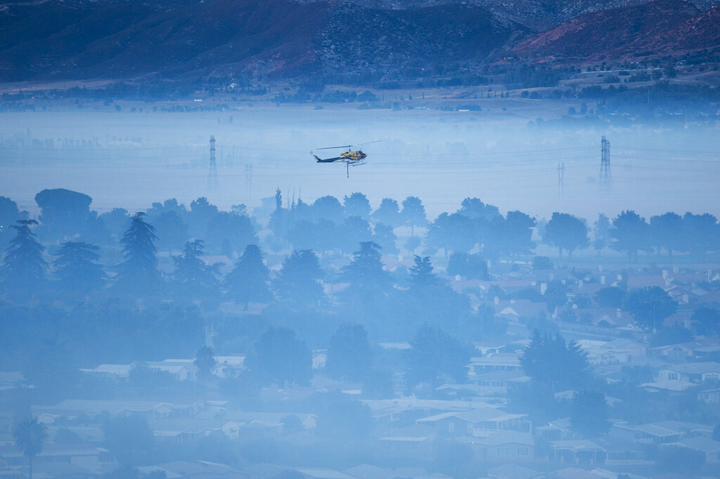 A helicopter flies over as smoke from the Apple Fire covers the city in Banning, Calif., Saturday, Aug. 1, 2020. (AP Photo/Ringo H.W. Chiu)