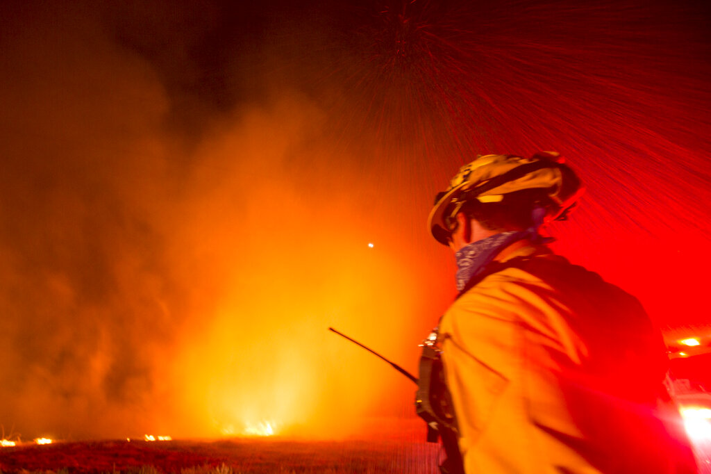 A firefighter watches as a helicopter drops water to the Apple Fire in Banning, Calif., Saturday, Aug. 1, 2020. (AP Photo/Ringo H.W. Chiu)