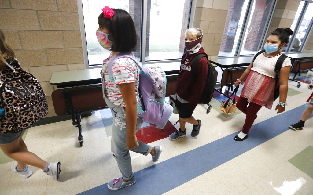 File---File picture taken Aug.5, 2020 shows pupils wearing masks to prevent the spread of COVID19 walking to class to begin their school day in Godley, Texas. As Germany’s 16 states start sending millions of children back to school in the middle of the global coronavirus pandemic, those used to the country’s famous “Ordnung” are instead looking at uncertainty, with a hodgepodge of regional regulations that officials acknowledge may or may not work.(AP Photo/LM Otero, File)