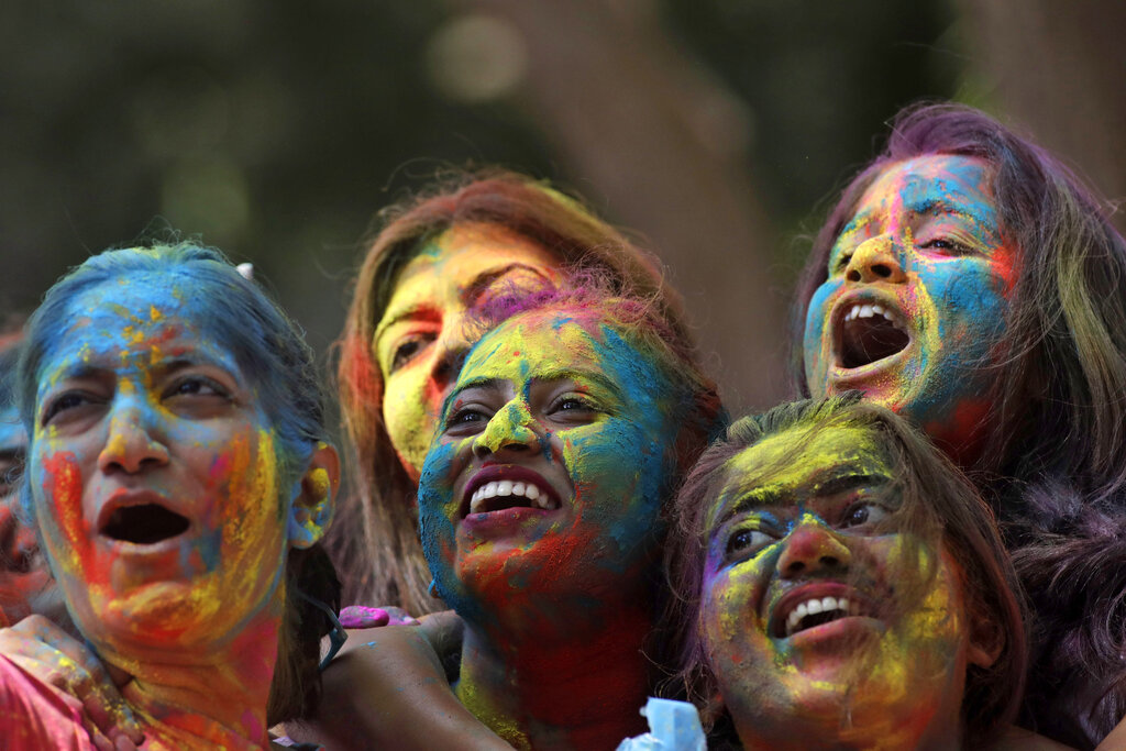 Women with their faces smeared with colored powder cheer during celebrations marking the Holi festival in Mumbai, India, Tuesday, March 10, 2020. Holi, the festival of colors heralds the arrival of spring (AP Photo/Rajanish Kakade)