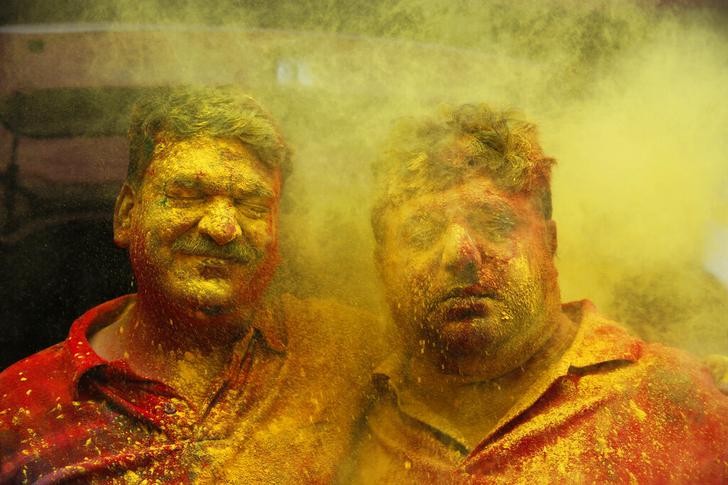 Indian men react as colored powder is thrown on their face during celebrations marking Holi, the Hindu festival of colors, in Prayagraj, India, Tuesday, March 10, 2020. (AP Photo/Rajesh Kumar Singh)
