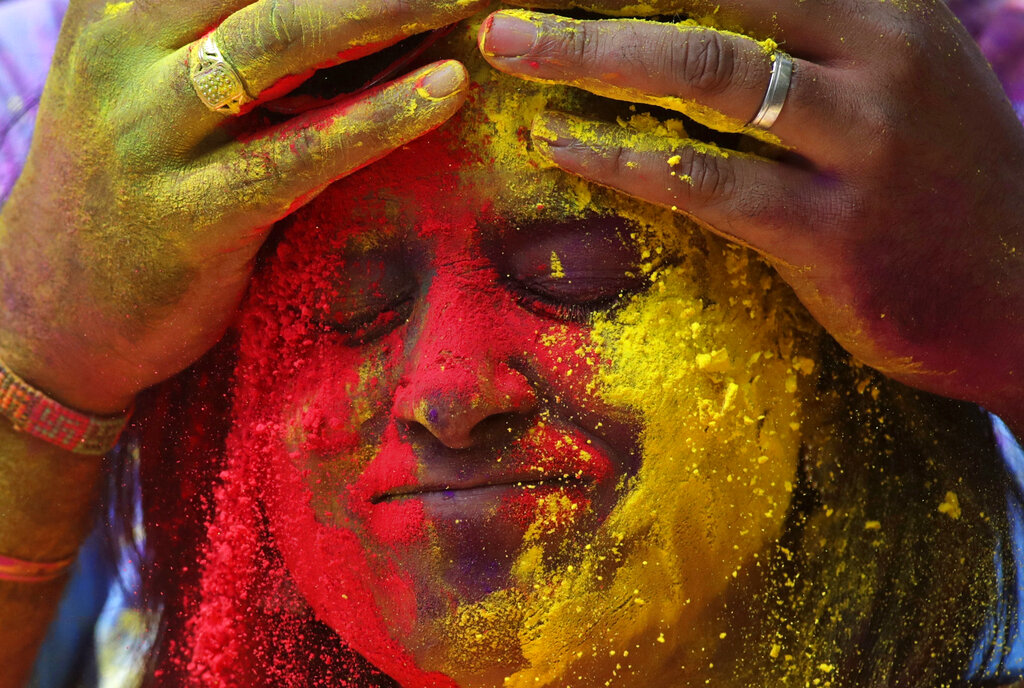 Face of a woman is smeared with colored powder during celebrations marking the Holi festival in Mumbai, India, Tuesday, March 10, 2020. Holi, the festival of colors heralds the arrival of spring (AP Photo/Rajanish Kakade)