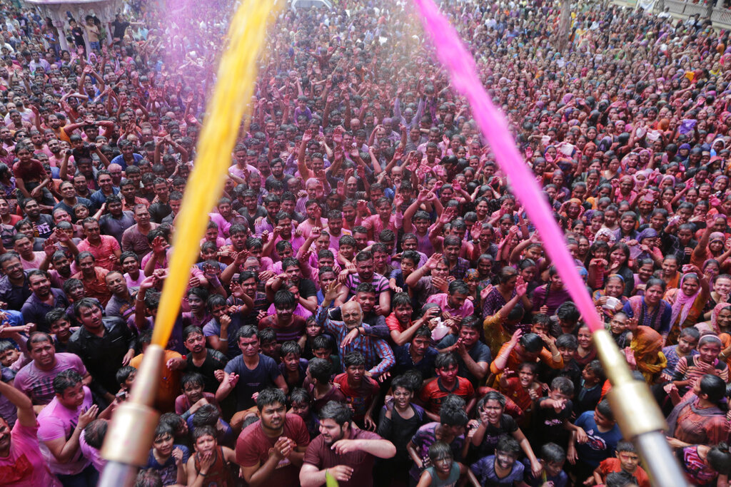Indian Hindu devotees cheer as colored powder and water is sprayed on them by a Hindu priest during celebrations marking Holi at the Swaminarayan temple in Ahmedabad, India, Tuesday, March 10, 2020. Holi, the Hindu festival of colors, also marks the advent of spring. (AP Photo/Ajit Solanki)
