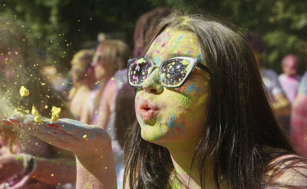 A woman blows colored powder from her hands during the Holi Festival in a city park in Kyiv, Ukraine, Saturday, Aug. 8, 2020. Ukrainians mark a popular ancient Hindu Holi Festival, also known as the festival of colors, or the festival of love, which signifies the victory of good over evil. Normally celebrated in spring, but postponed due to the coronavirus. (AP Photo/Efrem Lukatsky)