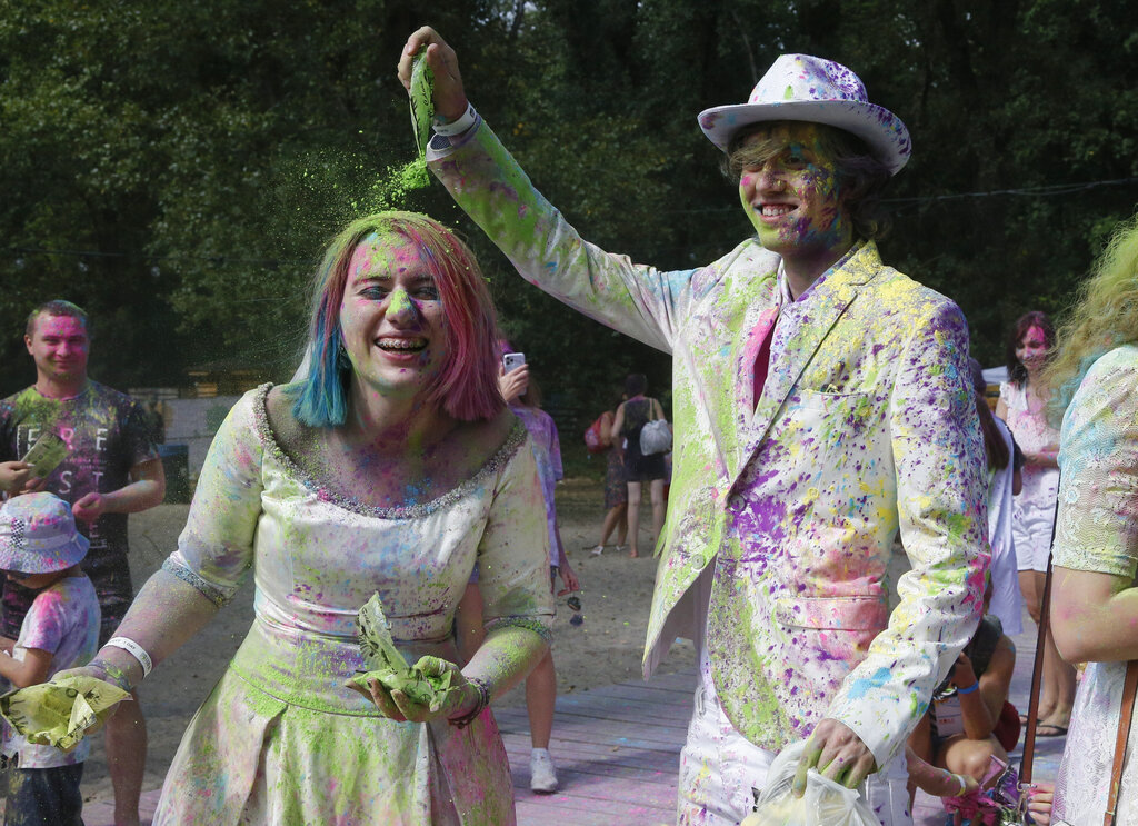 A bride and the groom, Maria and Andrew, throw colored powder on each other during the Holi Festival in a city park in Kyiv, Ukraine, Saturday, Aug. 8, 2020. Ukrainians mark a popular ancient Hindu Holi Festival, also known as the festival of colors, or the festival of love, which signifies the victory of good over evil. Normally celebrated in spring, but postponed due to the  coronavirus. (AP Photo/Efrem Lukatsky)