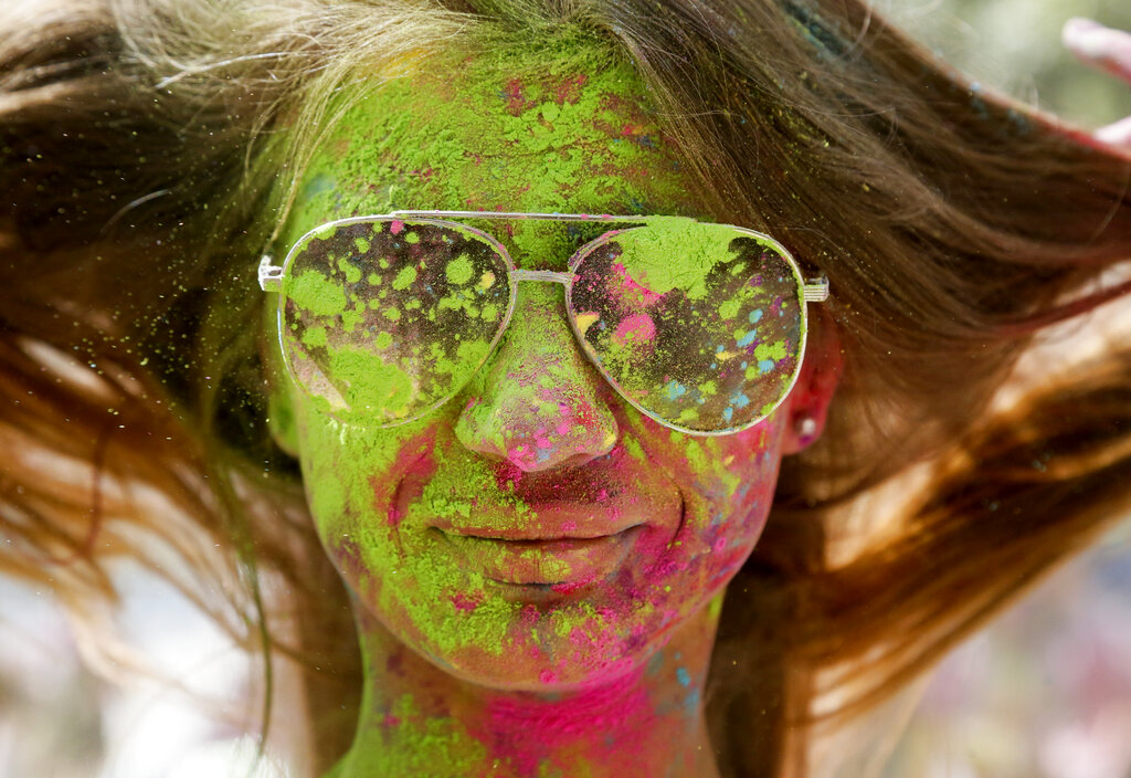 A woman smiles as her face is covered with colored powder during the Holi Festival in Kyiv, Ukraine, Saturday, Aug. 8, 2020. Ukrainians mark a popular ancient Hindu Holi Festival, also known as the festival of colors, or the festival of love, which signifies the victory of good over evil. Normally celebrated in spring, but postponed due to the  coronavirus. (AP Photo/Efrem Lukatsky)