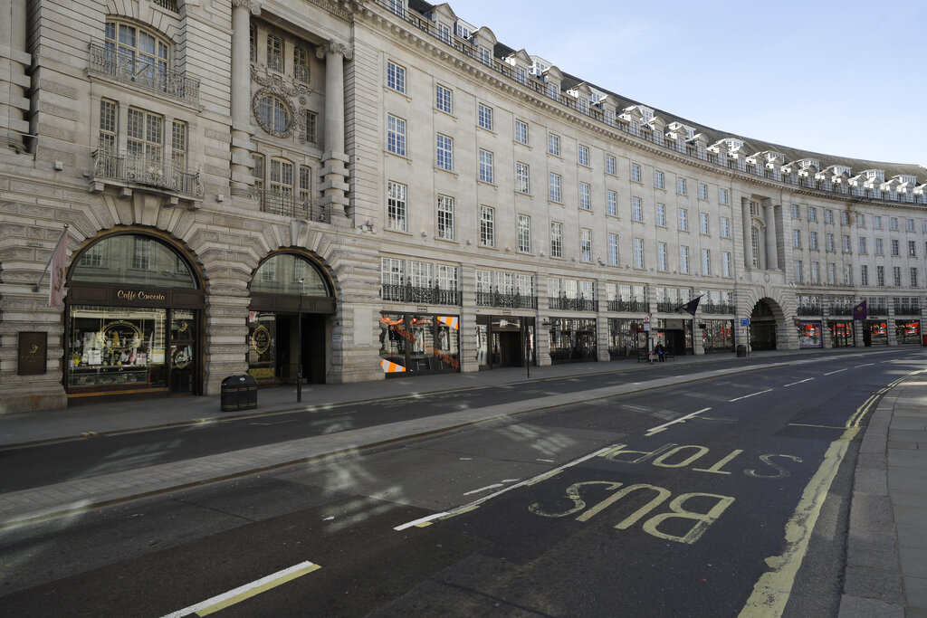 FILE - In this Tuesday, Mary 24, 2020 file photo, a lone commuter waits at a bus stop in an otherwise deserted Regent Street in London. The British economy grew by far less than anticipated during May, dampening hopes that the recovery from what is set to be one of the country’s deepest recessions in centuries will be rapid. The Office for National Statistics said Tuesday, July 14, 2020, that the economy grew by 1.8% in May from the previous month after some easing of the lockdown, such as encouraging those in construction or manufacturing to return to work.  (AP Photo/Matt Dunham, File)