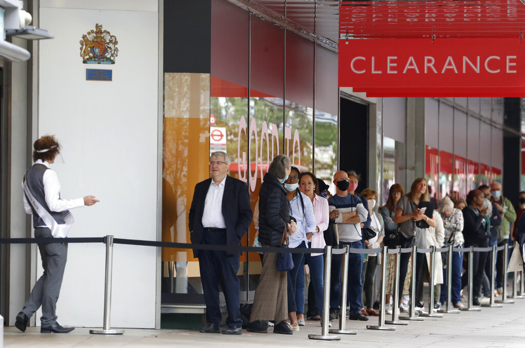 People, some wearing masks queue outside a John Lewis store, in London, Thursday, July 16, 2020. Unemployment across the U.K. has held steady during the coronavirus lockdown as a result of a government salary support scheme, but there are clear signals emerging that job losses will skyrocket over coming months. The Office for National Statistics said Thursday there were 649,000 fewer people, or 2.2%, on payroll in June when compared with March when the lockdown restrictions were imposed. (AP Photo/Alastair Grant)