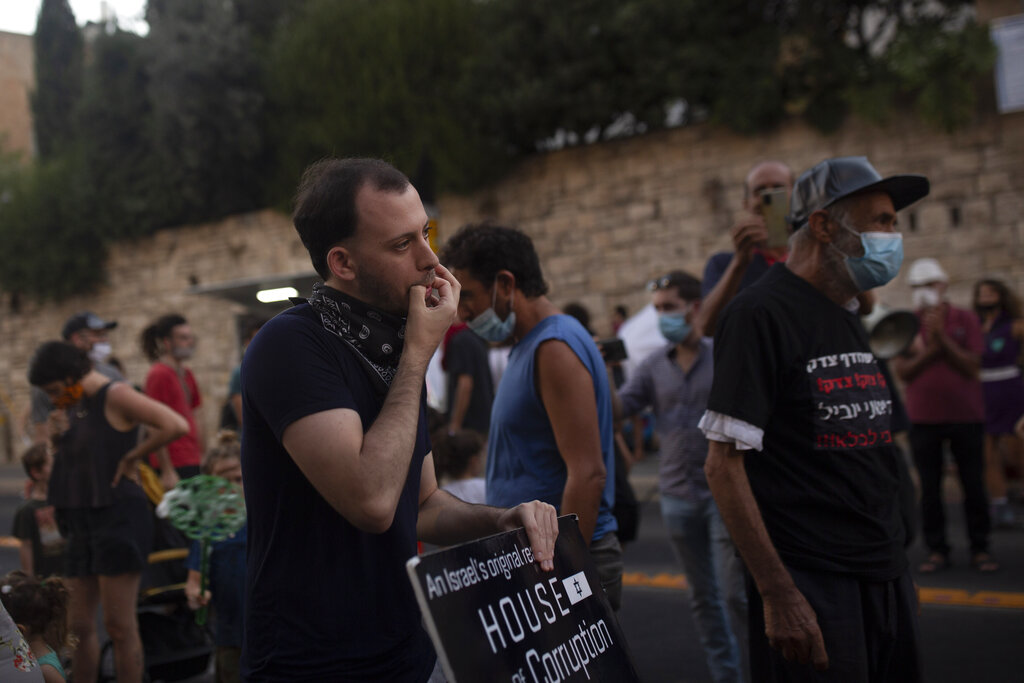 Shachar Oren, 25, whistles during a protest against Israel's Prime Minister Benjamin Netanyahu outside his residence in Jerusalem, Tuesday, Aug. 4, 2020. The boisterous rallies against Netanyahu have brought out a new breed of first-time protesters -- young, middle-class Israelis who have little history of political activity but feel that Netanyahu’s scandal-plagued rule and his handling of the coronavirus crisis have robbed them of their futures. (AP Photo/Maya Alleruzzo)