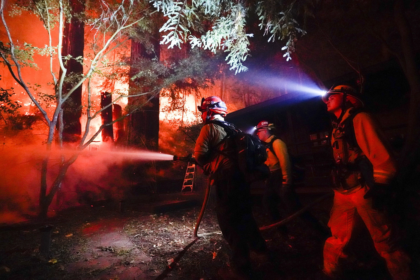 Firefighters battle the CZU August Lightning Complex Fire in the backyard of a home Friday, Aug. 21, 2020, in Boulder Creek, Calif. (AP Photo/Marcio Jose Sanchez)