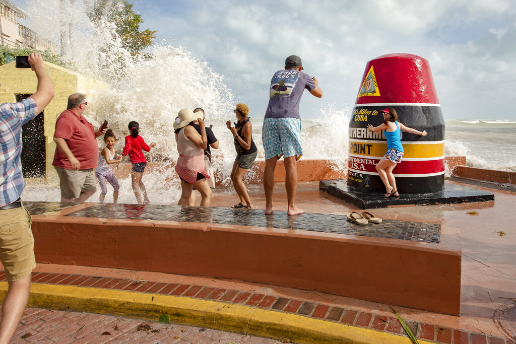 Visitors the Southernmost Point buoy in Key West brave the waves as the feeder bands of Hurricane Laura pass by Key West, Fla., on Monday, Aug. 24, 2020. (Rob O'Neal/The Key West Citizen via AP)