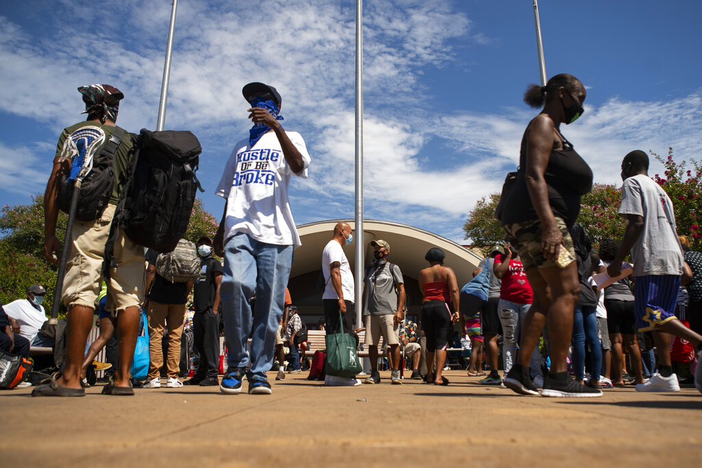 People wait in front of the Galveston Housing Authority offices to board charter busses that will evacuate them from Galveston Island to Austin in anticipation of impact from Hurricane Laura, Tuesday, Aug. 25, 2020, in Galveston. ( Mark Mulligan/Houston Chronicle via AP)