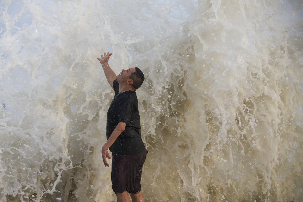 Water falls over Jimmy Villarreal, of Galveston, Texas as a wave hits the seawall while he was watching the surf stirred up by Hurricane Laura Wednesday, Aug. 26, 2020 in Galveston, Texas. (Brett Coomer/Houston Chronicle via AP)