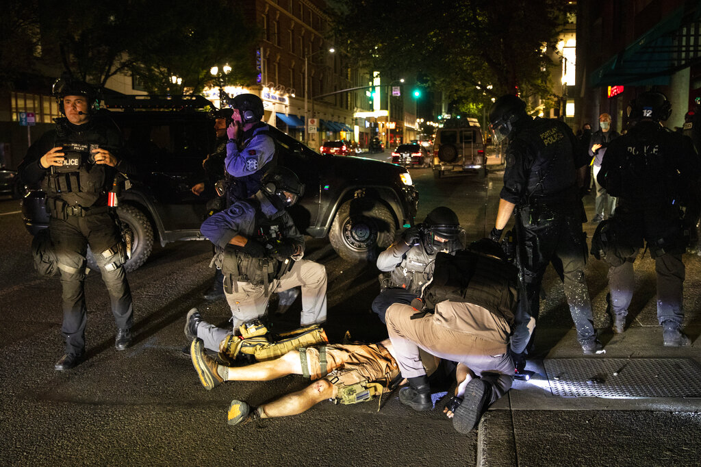 ADDS THE SHOOTING WAS FATAL - A man is treated after being shot Saturday, Aug. 29, 2020, in Portland, Ore. It wasn’t clear if the fatal shooting late Saturday was linked to fights that broke out as a caravan of about 600 vehicles was confronted by counterdemonstrators in the city’s downtown. (AP Photo/Paula Bronstein)