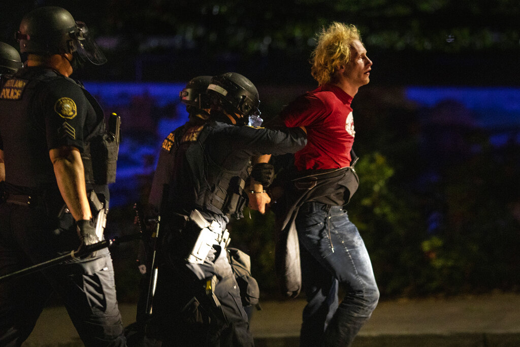 Portland police make arrests on the scene of the nightly protests at a Portland police precinct on Sunday, Aug. 30, 2020 in Portland, Ore. Oregon State Police will return to Portland to help local authorities after the fatal shooting of a man following clashes between President Donald Trump supporters and counter-protesters that led to an argument between the president and the city's mayor over who was to blame for the violence. (AP Photo/Paula Bronstein)