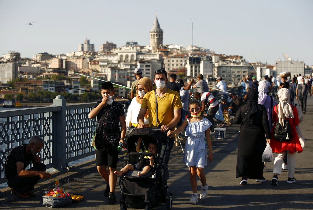 People walk along the Galata Bridge, with the historical Galata Tower in the background, in Istanbul, Friday, Aug. 7, 2020. (AP Photo/Emrah Gurel)