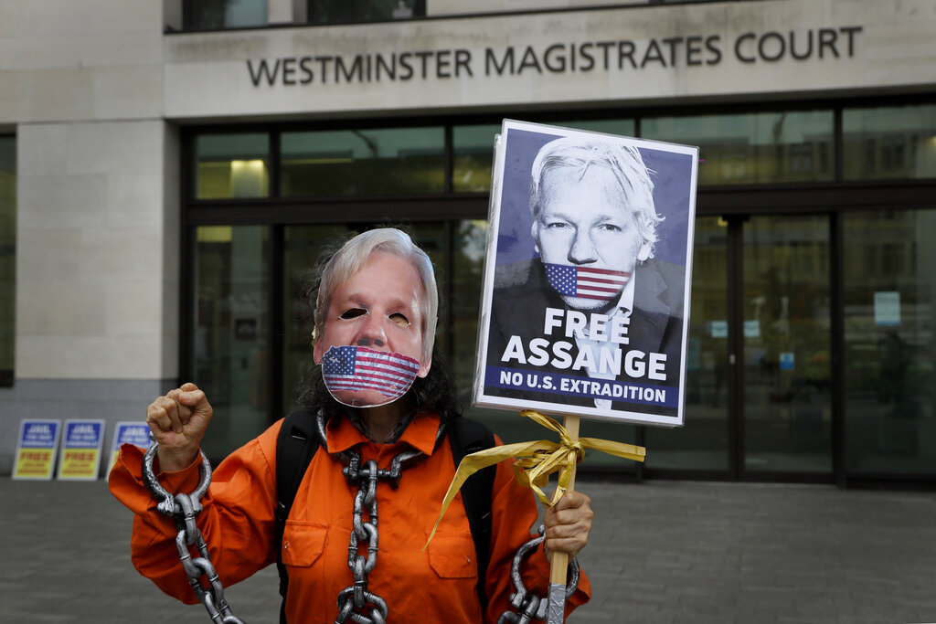 A demonstrator holds a banner outside Westminster Magistrates Court in London, Friday, Aug. 14, 2020. A final procedural hearing in the Julian Assange extradition case will take place at the court Friday. (AP Photo/Kirsty Wigglesworth)